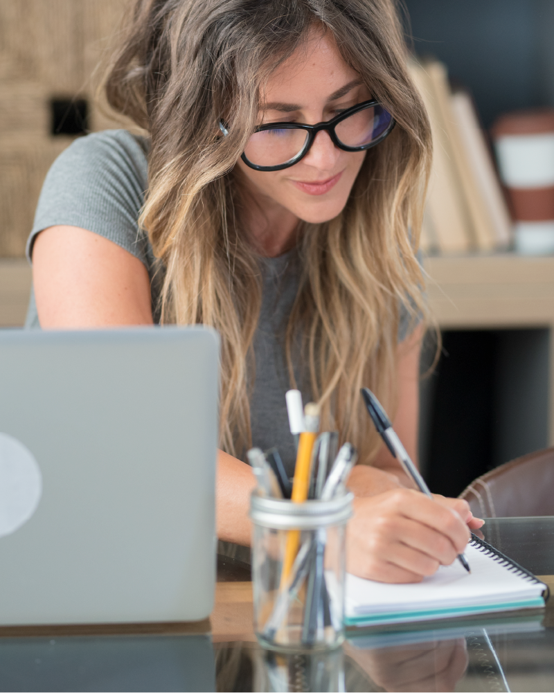 photo of woman writing on a notepad