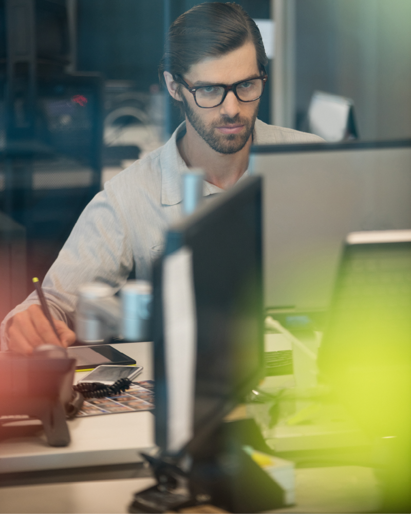 a man looking intently at a computer screen while writing code